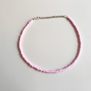 May include: A delicate pink beaded choker necklace with a silver chain clasp.
