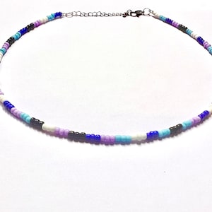 以下が含まれることがあります： 黒、白、青、紫のビーズが交互に並んだビーズチョーカーネックレスです。