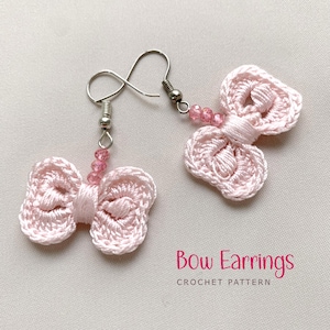 May include: A pair of light pink crochet bow earrings with silver-colored hooks and pink bead accents. The earrings are handmade and feature a delicate, feminine design. Text on the image reads "Bow Earrings CROCHET PATTERN."