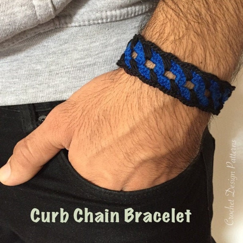 K&ouml;nnte beinhalten: Ein schwarzes und blaues geh&auml;keltes Bord&uuml;renkettenarmband am Handgelenk einer Person.