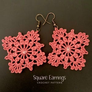 May include: Two pink, crocheted square earrings with a floral pattern and a central bead. The earrings hang from bronze-coloured ear wires. The text "Square Earrings CROCHET PATTERN" is visible at the bottom of the image.