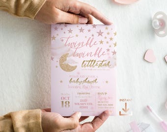 May include: A pink baby shower invitation with gold stars and a glittery crescent moon. The text reads "Twinkle Twinkle Little Star" and includes event details. The invitation is held by hands.