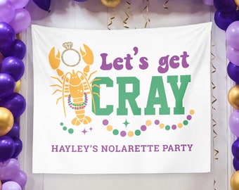 May include: White backdrop with the text "Let's get CRAY" in purple and green, featuring a lobster with a diamond ring. The backdrop is surrounded by purple, gold, and lavender balloons, creating a festive party atmosphere.