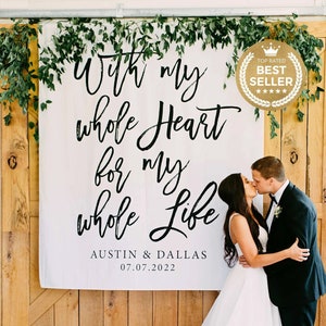 May include: A white banner with black calligraphy reads "With my whole Heart for my whole Life" with the names "Austin & Dallas" and the date "07.07.2022". A couple kisses in front of the banner. Greenery and a "Best Seller" badge are also visible.