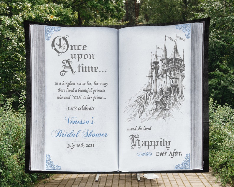 May include: A white book with a blue and gray design on the cover. The book is open to a page with a drawing of a castle and the text "Once upon a time... In a kingdom not so far, far away there lived a beautiful princess who said "YES" to her prince... Let's celebrate Venessa's Bridal Shower July 16th, 2021...and she lived Happily Ever After."
