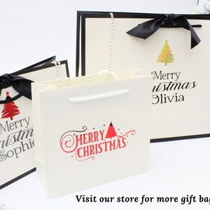 May include: Three white gift bags with black ribbon bows and Christmas tree designs. The bags have the text "Merry Christmas" and personalized names.