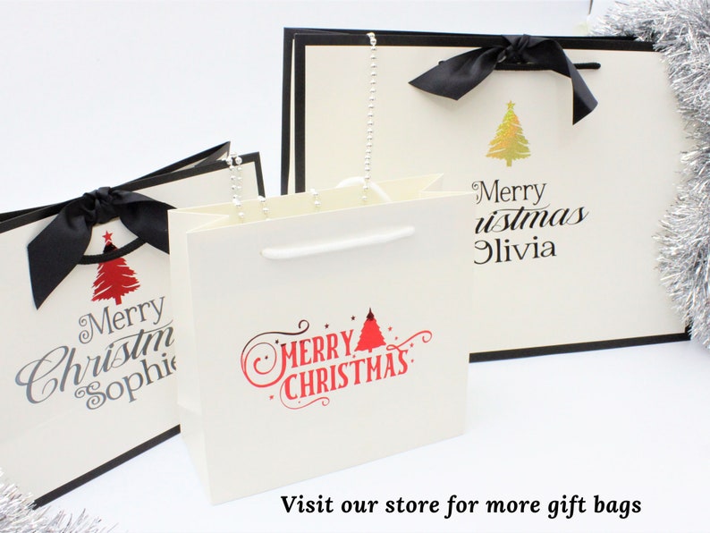 May include: Three white gift bags with black ribbon bows and Christmas tree designs. The bags have the text "Merry Christmas" and personalized names.