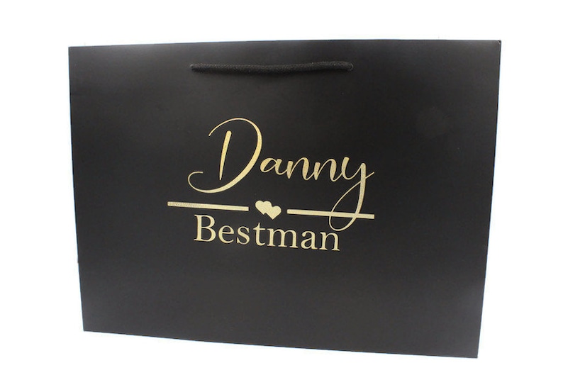 May include: Black gift bag with gold lettering that says "Danny Bestman" with two small hearts.