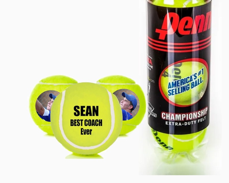 Pu&ograve; includere: Tre palline da tennis gialle con un messaggio personalizzato su una pallina che dice "SEAN BEST COACH Ever". La pallina ha anche una foto di una persona su di essa. Le palline sono in una lattina con il logo Penn e il testo "America's #1 Selling Ball" e "Championship Extra-Duty Felt".