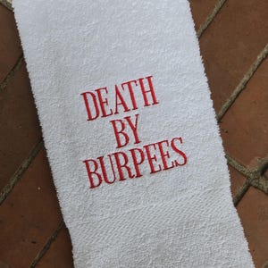 Könnte beinhalten: Weißes Handtuch mit rotem Sticktext "DEATH BY BURPEES".