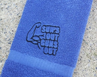 以下が含まれることがあります： 黒い刺繍でバイセップスと「Suns Out Guns Out」の文字が施された青いタオル。