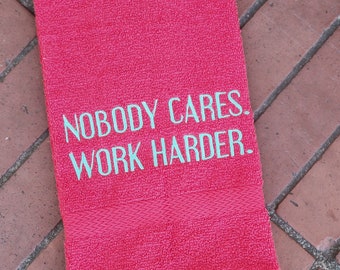 May include: A pink towel with the text "Nobody Cares. Work Harder." embroidered in teal.