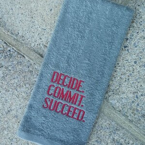 May include: Gray hand towel with the words "Decide Commit Succeed" embroidered in red.