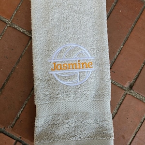 May include: A gray hand towel with a white volleyball and the name "Jasmine" embroidered in orange.