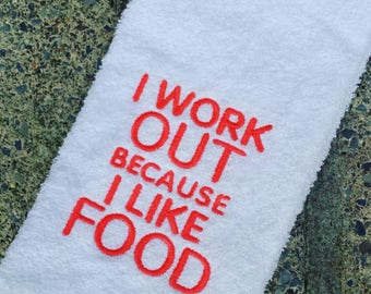 May include: White kitchen towel with red embroidered text that reads "I work out because I like food".