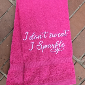 Może przedstawiać: Różowy ręcznik kąpielowy z białym haftem, na którym widnieje napis "Nie pocę się, ja błyszczę".