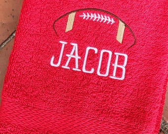 May include: Red bath towel with white embroidery of a football and the name "JACOB".