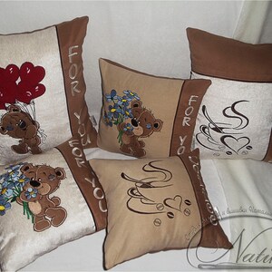 May include: Four decorative throw pillows with embroidered designs. Two pillows feature a brown teddy bear with a heart and a cup of coffee. One pillow has a teddy bear holding a bouquet of blue flowers. The last pillow has a teddy bear holding red balloons. All pillows have the text "For You" on them.
