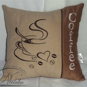 May include: A brown and beige throw pillow with embroidered coffee cup and steam design. The word "Coffee" is embroidered on the side of the pillow in white.