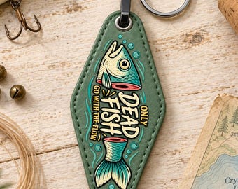 May include: A diamond-shaped olive green motel-style keychain featuring a graphic of a fish split into two parts. The text reads "ONLY DEAD FISH GO WITH THE FLOW" in a stylized font. The keychain includes a black metal clasp and a silver ring.