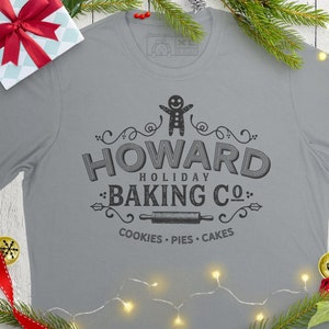 May include: A gray t-shirt with a vintage-style logo that says "Howard Holiday Baking Co." with a gingerbread man, rolling pin, and the words "Cookies - Pies - Cakes".