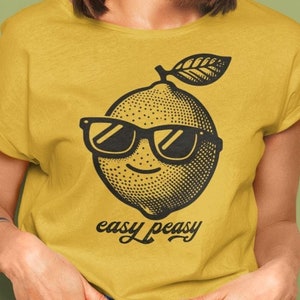 May include: A yellow t-shirt with a black and white illustration of a lemon wearing sunglasses and the text "easy peasy".