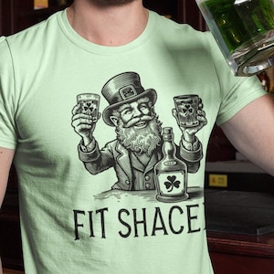 Get Fit Shaced in style with this cheeky tee! Featuring a mischievous leprechaun chugging a frothy pint, this shirt is a perfect blend of luck, laughter, and a play on words. Whether you're lifting pints or lifting weights, this bold design lets everyone know you're here for gains—and good times. Sláinte to fitness, fun, and maybe a little mischief!