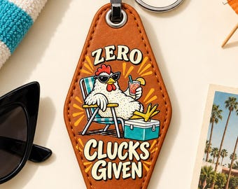 May include: A diamond-shaped brown motel-style keychain featuring a graphic of a chicken wearing sunglasses, sitting in a beach chair with a drink and a cooler. The text reads ZERO CLUCKS GIVEN. It includes a silver metal ring and a black clasp.