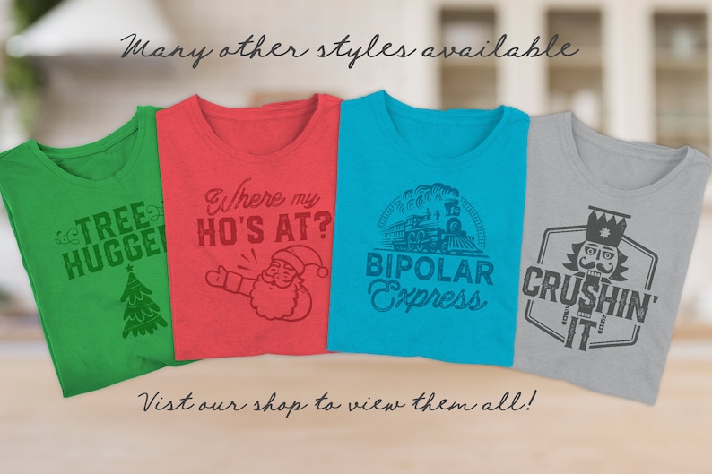 Op de afbeelding: Vier verschillende T-shirts met humoristische kerstthema-ontwerpen. De shirts zijn groen, rood, blauw en grijs. De ontwerpen omvatten een kerstboom, de kerstman, een trein en een notenkraker. De tekst op de shirts luidt "Tree Hugger", "Where my Ho's at?", "Bipolar Express" en "Crushin' It".