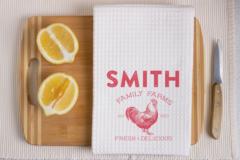 以下が含まれることがあります： 赤い文字で「SMITH FAMILY FARMS EST 1920 FRESH & DELICIOUS」と書かれた白いキッチンタオル。タオルの中央には赤い雄鶏のイラストが描かれている。