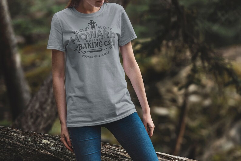 May include: A gray t-shirt with a vintage-style logo that says "Howard Holiday Baking Co." with a gingerbread man graphic and the text "Cookies - Pies - Cakes".