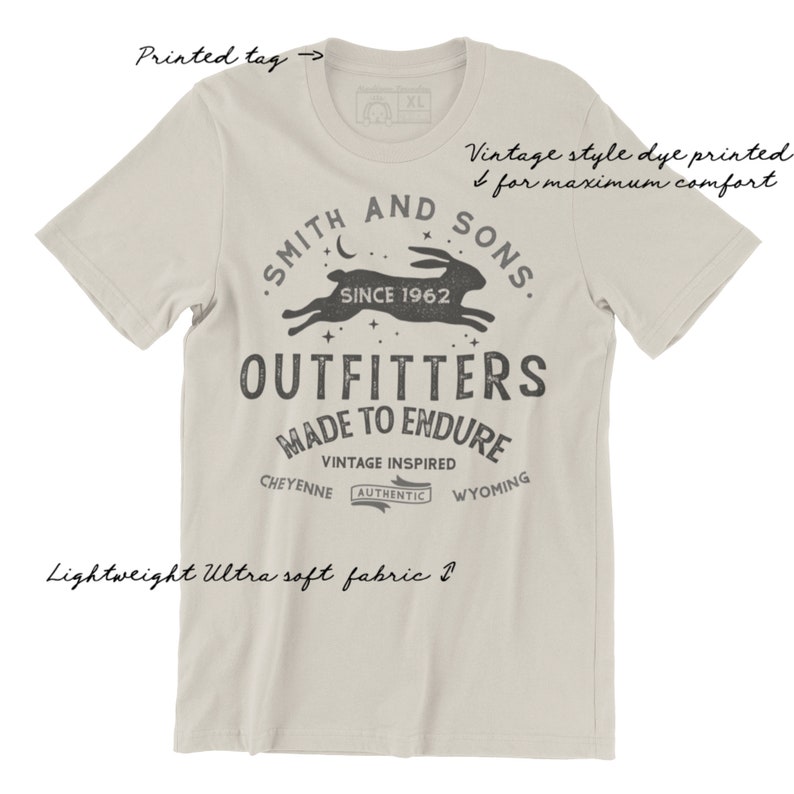 May include: A light beige t-shirt with a vintage-style print of a rabbit running with stars and the text "Smith and Sons, Since 1962, Outfitters, Made to Endure, Vintage Inspired, Cheyenne, Authentic, Wyoming".