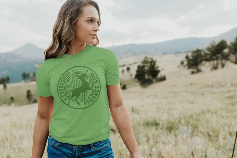Op de afbeelding: Een groen T-shirt met een ronde afbeelding van een hert met de tekst "Everybody Mon France" eromheen.