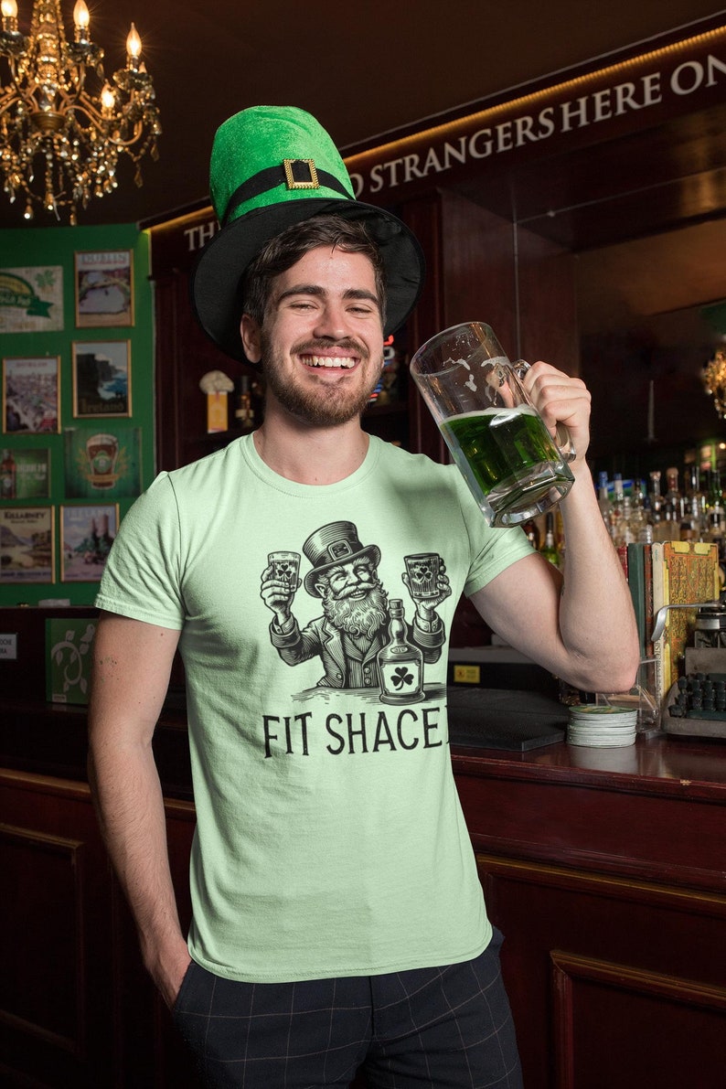 Get Fit Shaced in style with this cheeky tee! Featuring a mischievous leprechaun chugging a frothy pint, this shirt is a perfect blend of luck, laughter, and a play on words. Whether you're lifting pints or lifting weights, this bold design lets everyone know you're here for gains—and good times. Sláinte to fitness, fun, and maybe a little mischief!
