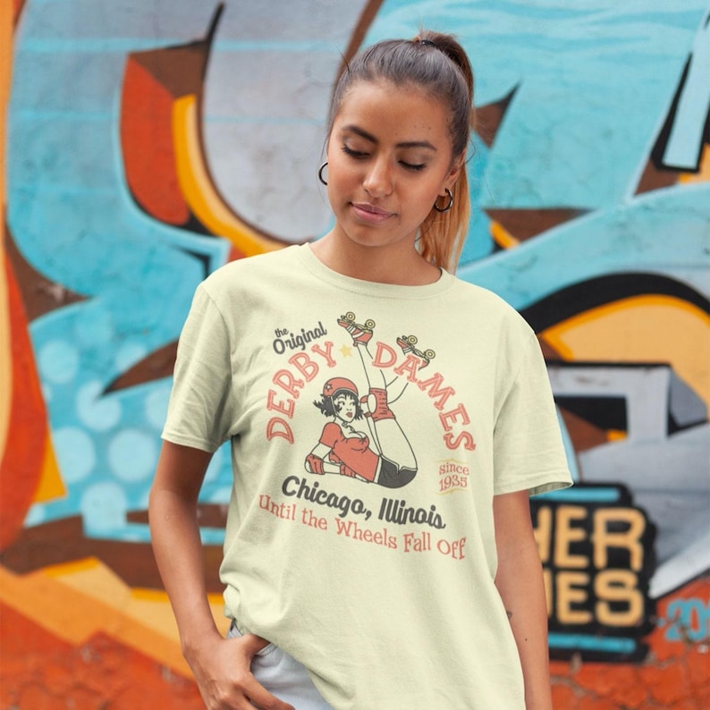 Roll back in time with our fierce Derby Dames tee, featuring a bold retro pinup girl laced up and ready to roll. This vintage-inspired design captures the grit and glam of classic roller derby—fishnets, attitude, and skates flying. Perfect for derby queens, fans, or anyone who lives life on eight wheels. Soft, fitted, and full of old-school fire—this shirt screams speed, sass, and sisterhood. Lace up and let it ride!