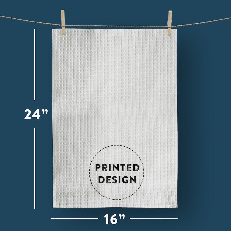 以下が含まれることがあります： 白のワッフル織りのキッチンタオルで、中央に「PRINTED DESIGN」と書かれた黒い円があります。タオルの幅は16インチ、長さは24インチです。