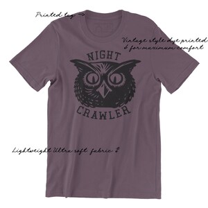 May include: Purple short-sleeved t-shirt with a black and white illustration of an owl with the text "NIGHT CRAWLER" printed on the front.