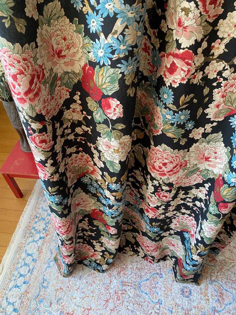 May include: Black floral fabric with large pink, red, and cream-colored peony blooms, accented by blue and green foliage. The fabric has a dark background and a detailed, vintage-inspired design, suitable for curtains or upholstery.