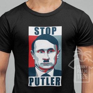 May include: Black t-shirt with a graphic design featuring a portrait of a man with a mustache, with the words "STOP PUTLER" in white block letters. The design has red, white, and blue color blocks.