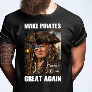 May include: Black t-shirt featuring a graphic of a person in pirate attire, including an eye patch with the American flag. The shirt displays the text "MAKE PIRATES GREAT AGAIN" and "Captain Chaos".