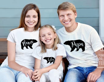 May include: A family of three wearing white t-shirts with black bear silhouettes and the words "Mama", "Papa", and "Baby".