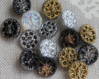 May include: Assortment of decorative buttons in various colors and designs, including silver, gold, black, and iridescent. The buttons have intricate patterns and are perfect for crafting projects.