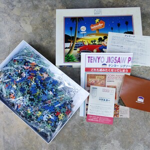 May include: A complete 1000-piece jigsaw puzzle in a white box with a clear plastic bag containing the puzzle pieces. The puzzle is of a cartoon scene with Mickey Mouse and a diner. The box has the text "TENYO JIGSAW PUZZLE" and "CORK PAPER JIGSAW PUZZLE" on it.