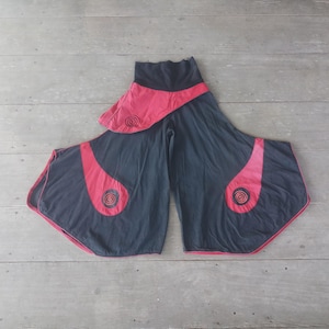 May include: Black and red wide-leg pants with a unique design. The pants feature a high waist and flared legs. Red accents with spiral designs are on the sides. The pants are made of a soft, flowing fabric, perfect for casual wear.