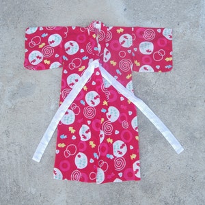 May include: A red and white patterned kimono with a white sash. The kimono has a swirling pattern of circles, dots, and fish.
