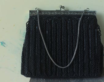 May include: A black beaded evening bag with a silver chain strap and a silver clasp.