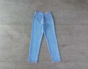 Puede incluir: Un par de pantalones vaqueros de mezclilla azul claro con un estilo clásico de cinco bolsillos. Los pantalones tienen cintura alta y pierna recta.