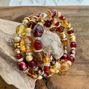 Peut inclure: Un bracelet à plusieurs rangs avec des perles ambrées, bordeaux et dorées. Le bracelet comprend des perles facettées, rondes et ovales avec des accents argentés. Le design est un mélange de textures et de couleurs, créant un bijou unique.