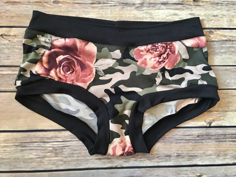 May include: Black and green underwear with a camouflage and floral print. The underwear has a black elastic waistband and trim.