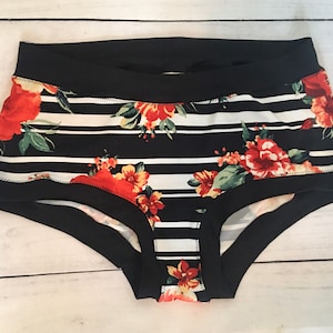 May include: Black and white striped underwear with a floral print featuring red, orange, and yellow flowers. The underwear has a black elastic waistband.